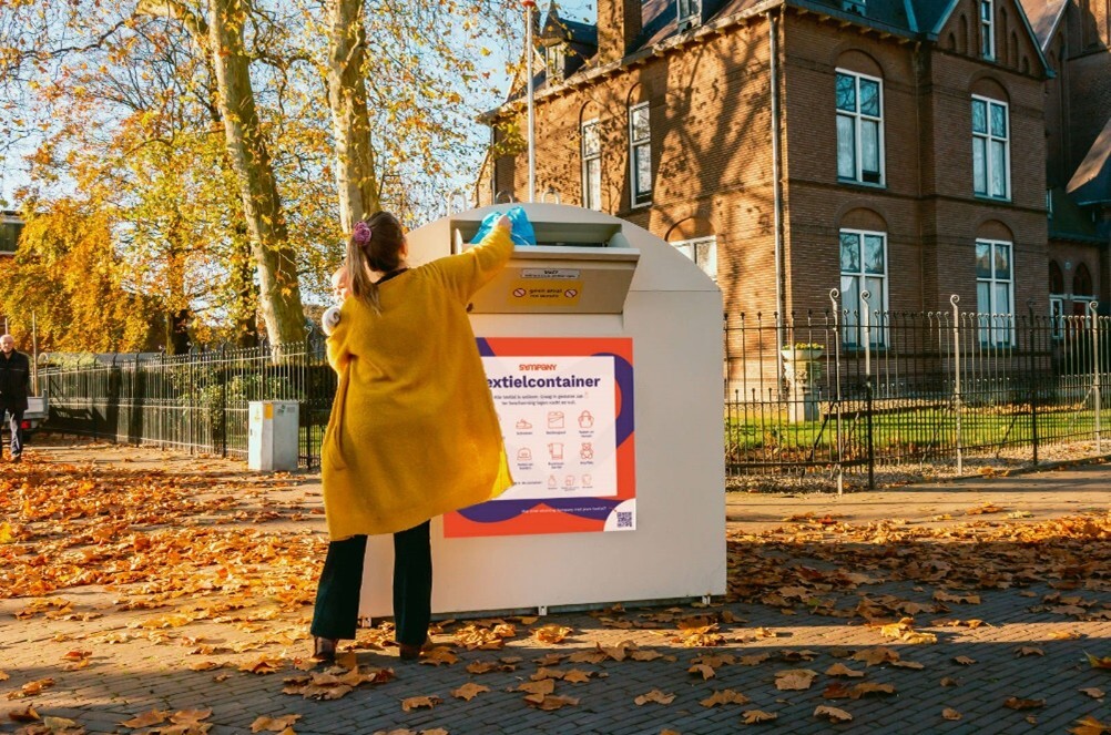 Afbeelding van vrouw die een zak met textiel in de textielcontainer van Sympany doet