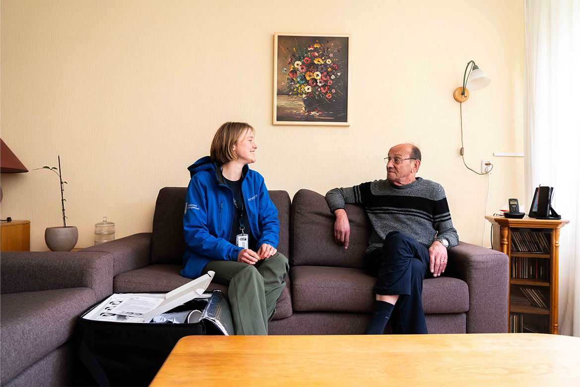 Een vrijwilliger van het Regionaal Energieloket zit op de bank bij een inwoner het gesprek te voeren over verduurzaming