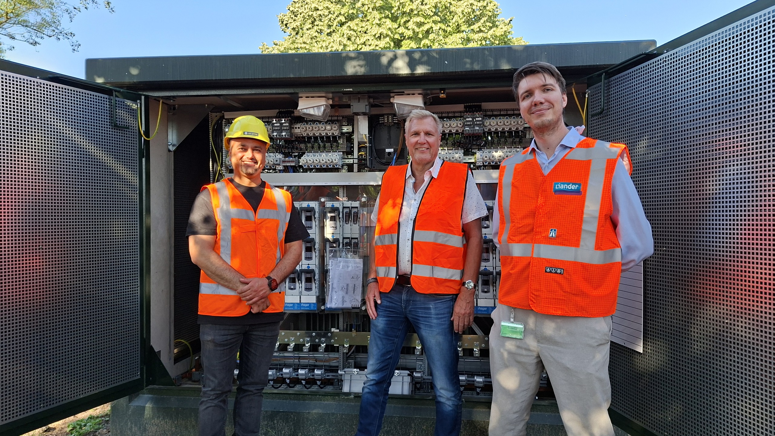 Wethouder Dolf Kistemaker samen met twee collega's van Liander voor een transformatorhuisje.