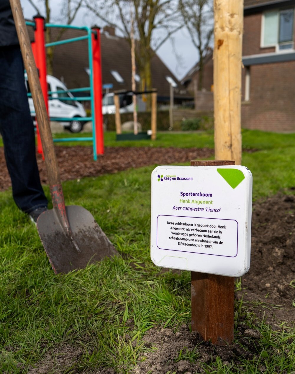 Naambord bij de geplante boom. Op het bord staat: Sportersboom Henk Angenent, Acer campestre 'Lienco'. Deze veldesdoorn is gepland door Henk Angenent, als eerbetoon aan de in Woubrugge geboren Nederlands schaatskampioen en winnar van de Elfstedentocht in 1997.