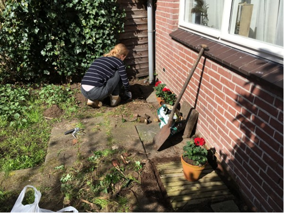 Sfeerbeeld van een vrouw die in de tuin onkruid aan het verwijderen is.